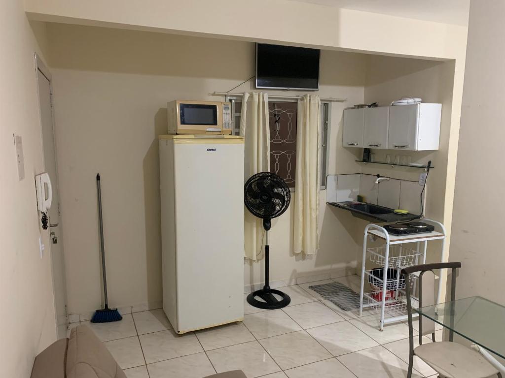 a small kitchen with a refrigerator and a microwave at 102 verão kit exclusiva in Brasilia