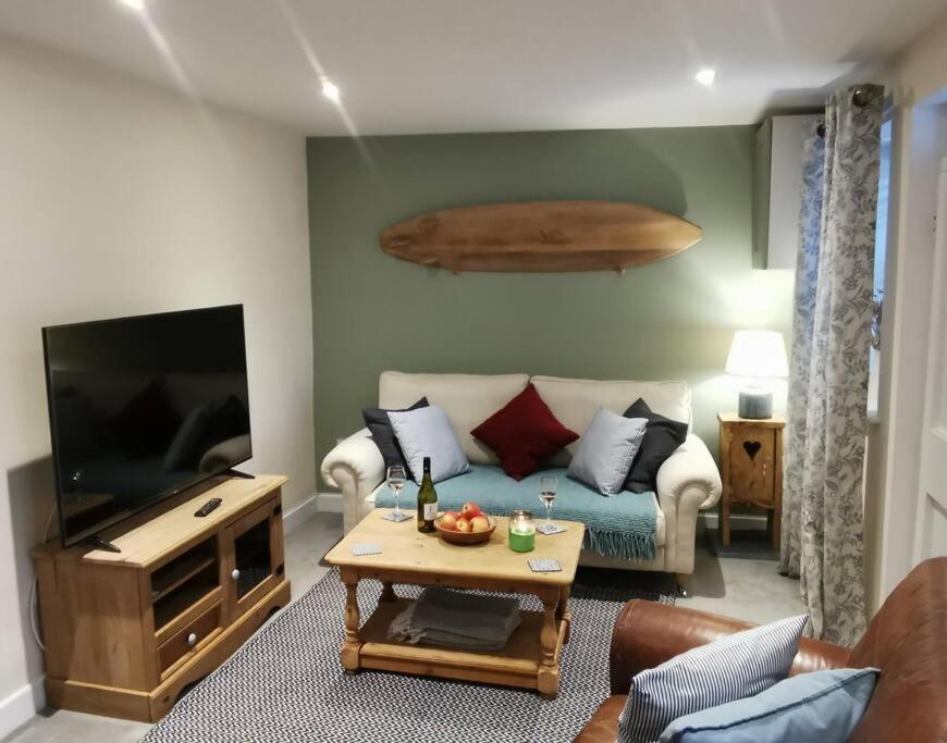 a living room with a couch and a tv at Cosy Cottage in a quaint village in North Devon. in Bideford