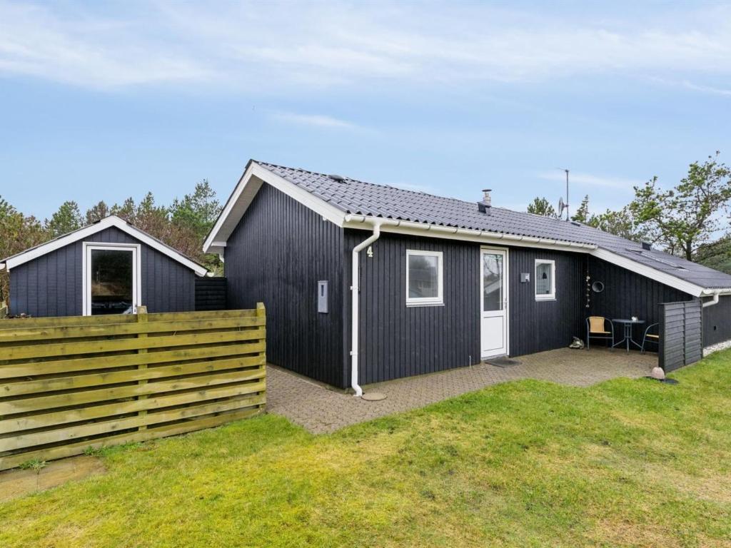 een zwart huis met een hek ervoor bij Holiday Home Tammo - 900m from the sea in NW Jutland by Interhome in Torsted