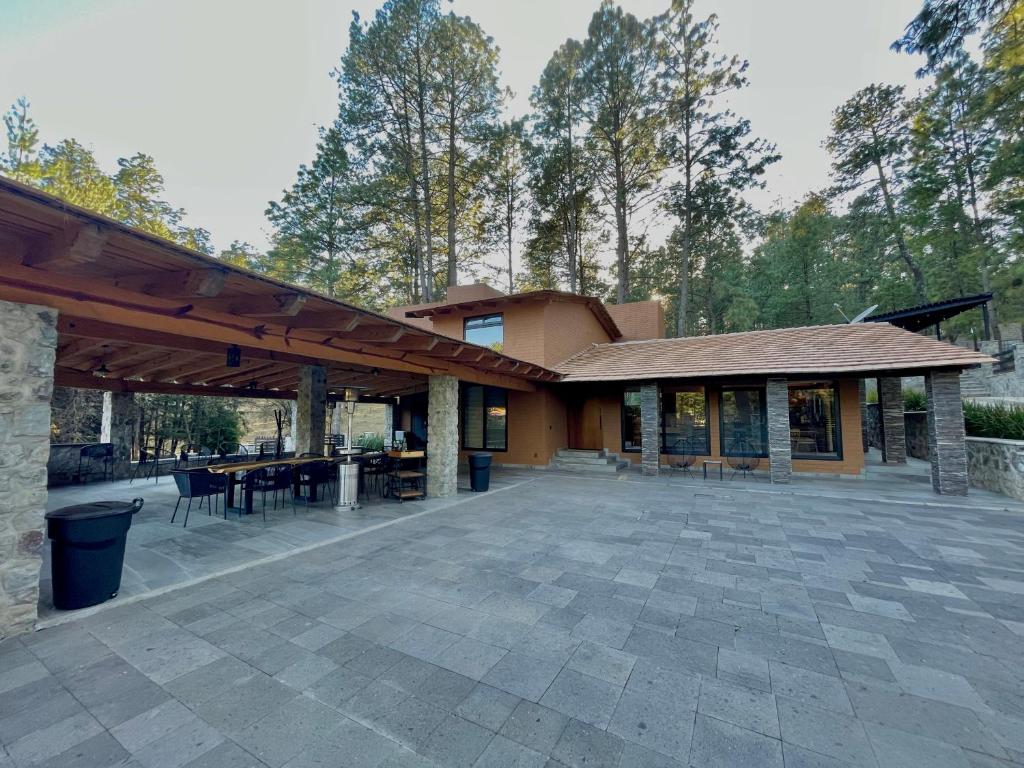 a patio with a building with a table and chairs at Cabaña en Tapalpa, Cabaña Monarca in Tapalpa