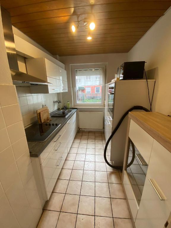 a kitchen with white cabinets and a tile floor at Monteurwohnung Heilbronn nahe Neckarsulm in Heilbronn