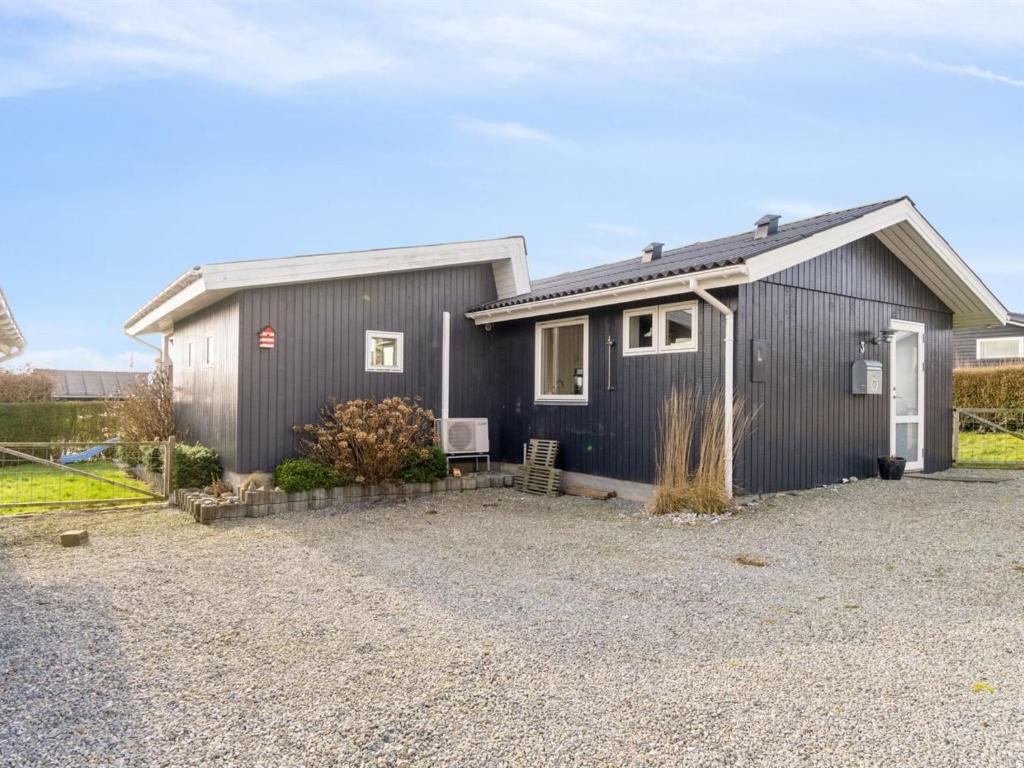 a gray house with a gravel driveway in front of it at Holiday Home Gyrid - 150m from the sea in Djursland and Mols by Interhome in Rønde