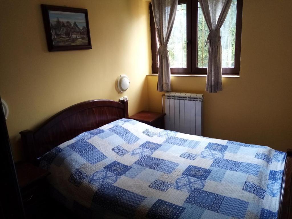 1 dormitorio con edredón en una cama con ventana en JetSet Apartmani, en Zlatibor