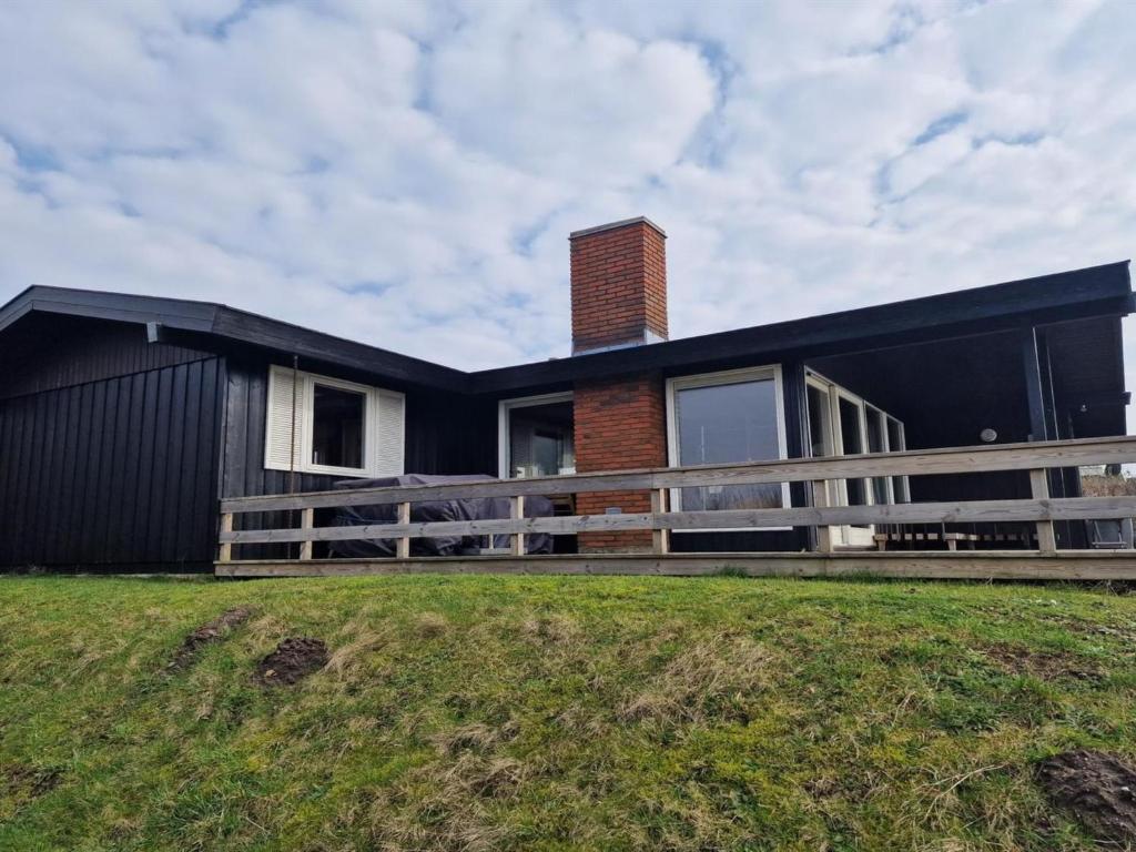 una casa negra con una chimenea de ladrillo en la parte superior de un campo en Holiday Home Rothger - 200m from the sea in SE Jutland by Interhome, en Sønderby