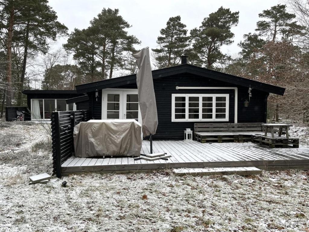a black cabin with an umbrella and a deck at Holiday Home Giertrud - 1-1km from the sea in Sealand by Interhome in Vig