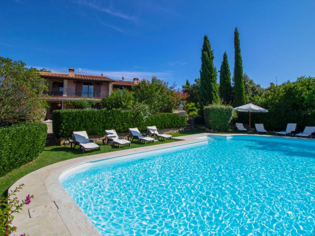 a swimming pool in a yard with chairs and a house at Villa La Gattaiola by Interhome in Montemerano