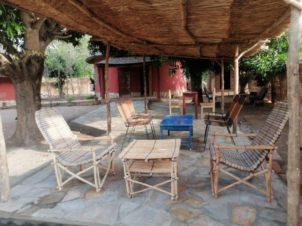 Le Jardin de L'Atacora في Natitingou: مجموعة من الكراسي والطاولات تحت سقف خشبي