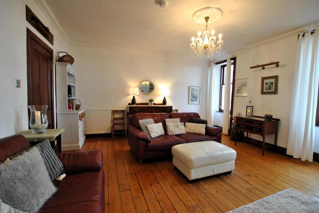 a living room with couches and a chandelier at Kittiwake House- charming coastal home in Saint Monance