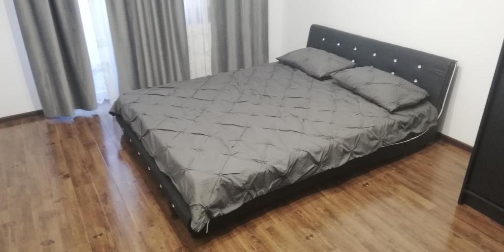 uma cama grande num quarto com piso em madeira em Apartament 2 camere Ultracentral em Tîrnăveni