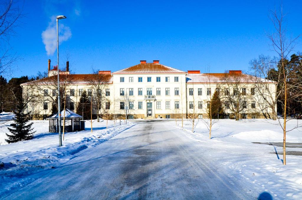 a large white building with snow on the ground at Hostel Bjorkenheim in Seinäjoki