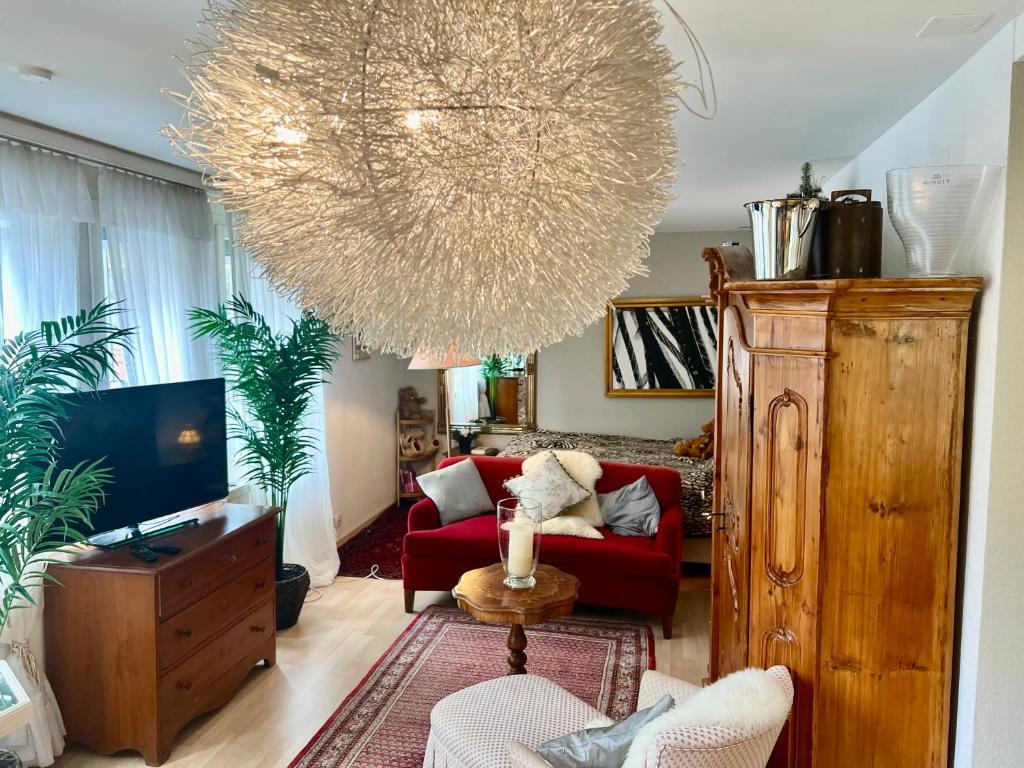 a living room with a red couch and a large chandelier at Romantic Space in Nussbaumen
