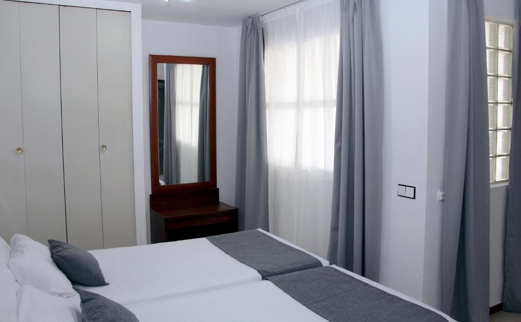 - une chambre avec un lit, un miroir et une fenêtre dans l'établissement Hospedium Hotel Blu Torre de Sevilla, à Torre de la Reina