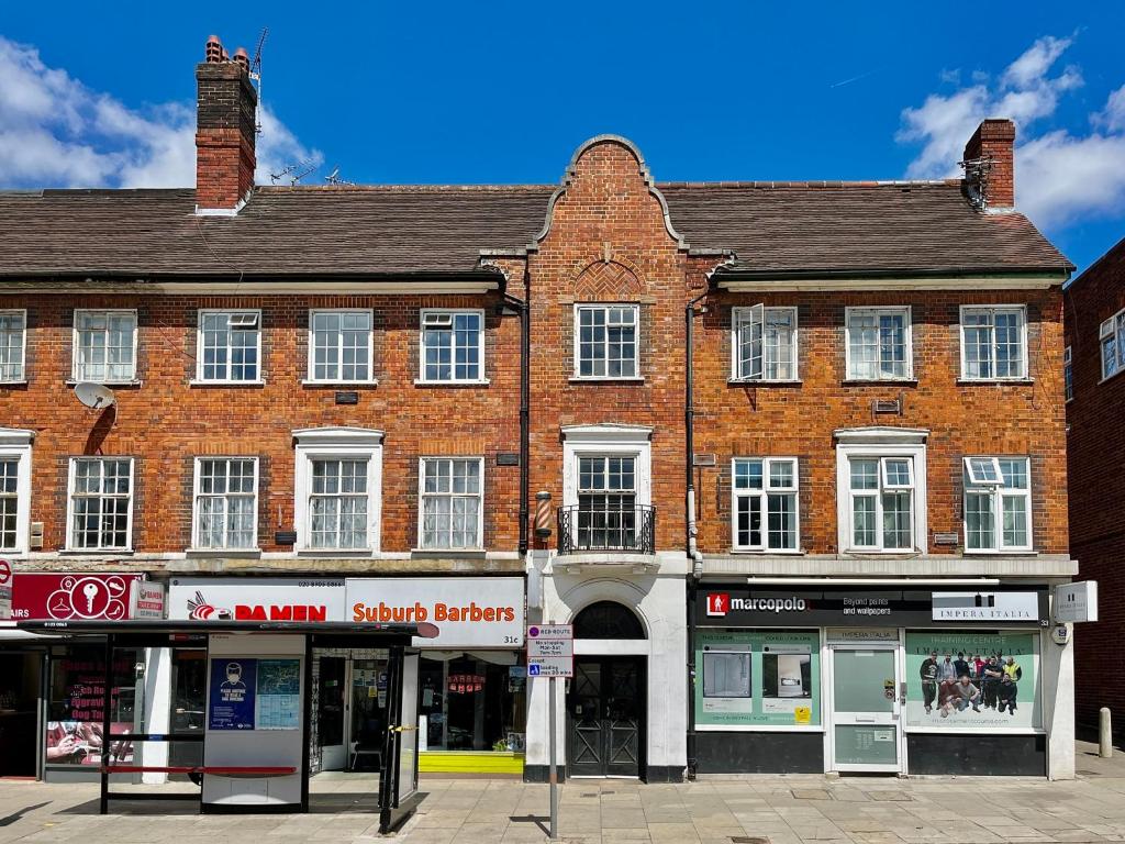 um grande edifício de tijolos com lojas numa rua em Hampstead 4-bedrooms condo apartment em Londres