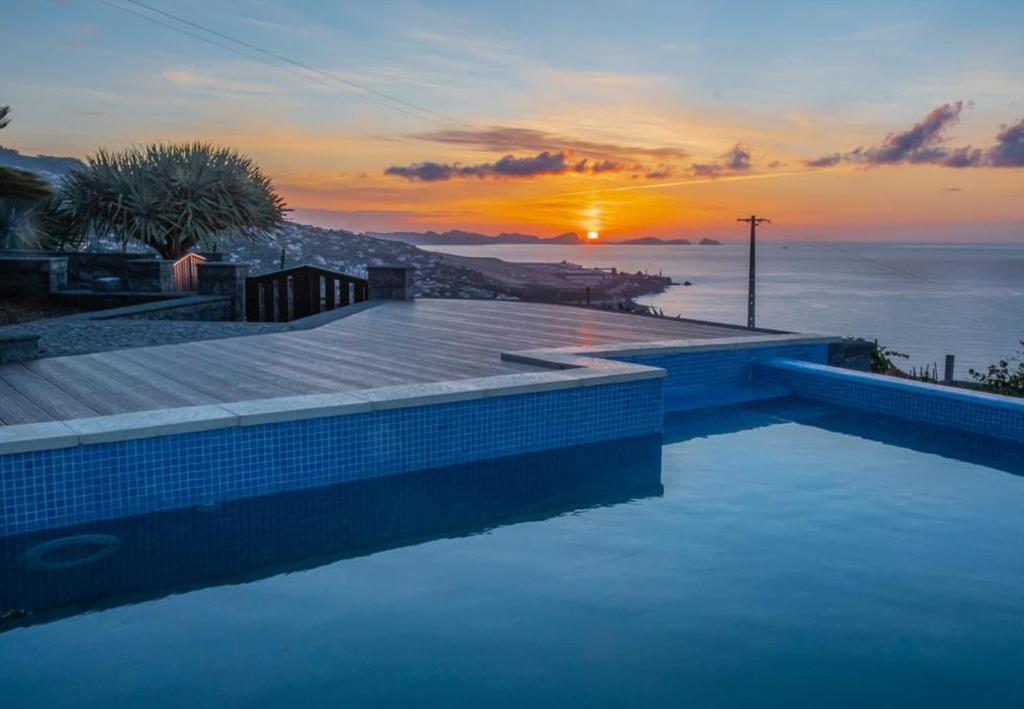 einen Pool mit Sonnenuntergang im Hintergrund in der Unterkunft Villa Sunrise View by Madeira Sun Travel in Santa Cruz