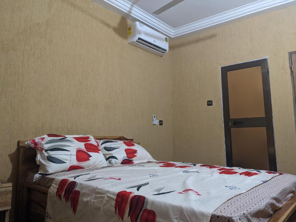 a bedroom with a bed with red flowers on it at STUDIO 3 Climatisé et Ventilateur plafonnier Et Wifi Gratuit A 6 Nuitées de Réservation in Lomé