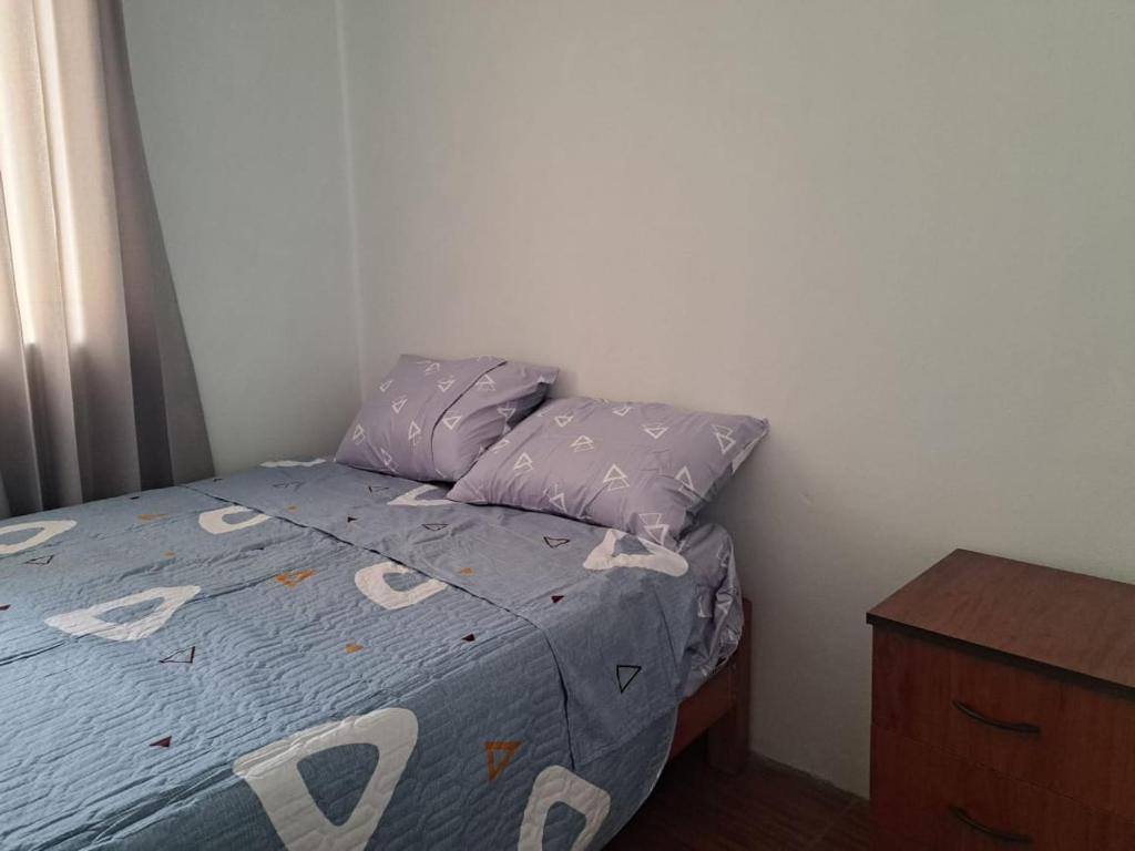 een kleine slaapkamer met een bed met paarse lakens en kussens bij Departamento de 3 pisos a 9 cuadras de la plaza in Ayacucho