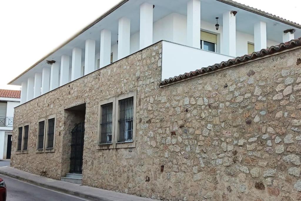 a building with windows and a stone wall at Casa Rural Las Parras 48 in Malpartida de Cáceres