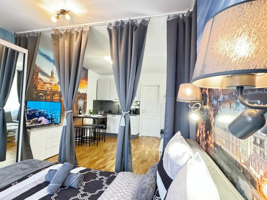 um quarto com uma cama com cortinas azuis e uma cozinha em New modern-style apartment with balcony in the Prague 2 em Praga