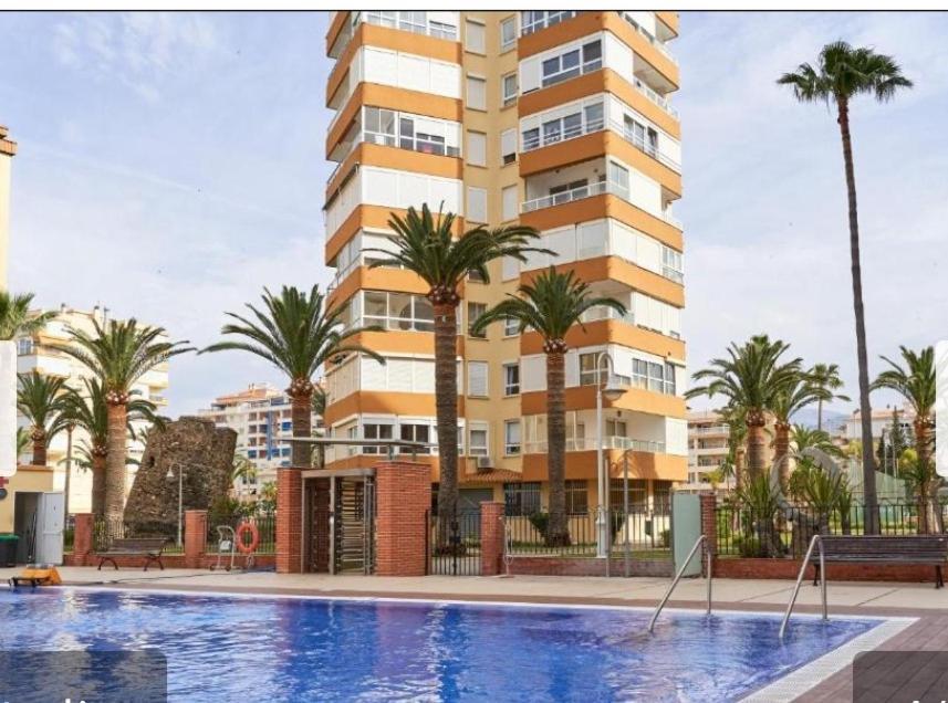 a swimming pool in front of a building with palm trees at Casa Rosa in Algarrobo-Costa