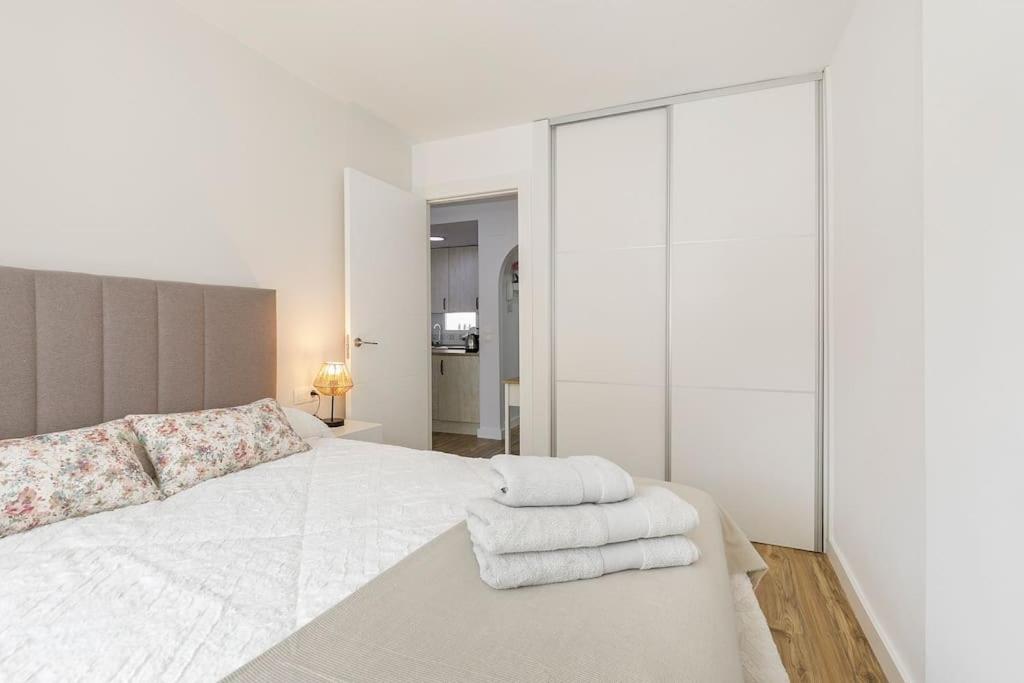 - une chambre blanche avec un lit et des serviettes dans l'établissement Apartamento Carmela, à Monachil