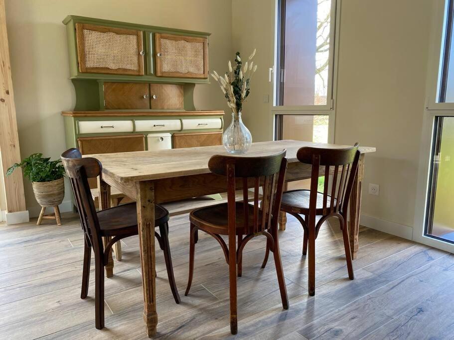 une table de salle à manger avec des chaises et un vase dessus dans l'établissement Gîte paisible au style rétro, à Réty