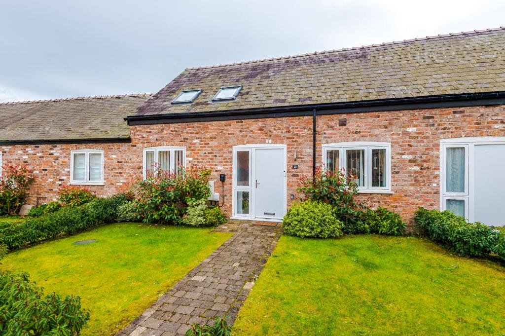 a brick house with a lawn in front of it at Number 21: A Breathtaking Chester Cottage with Parking in Mollington