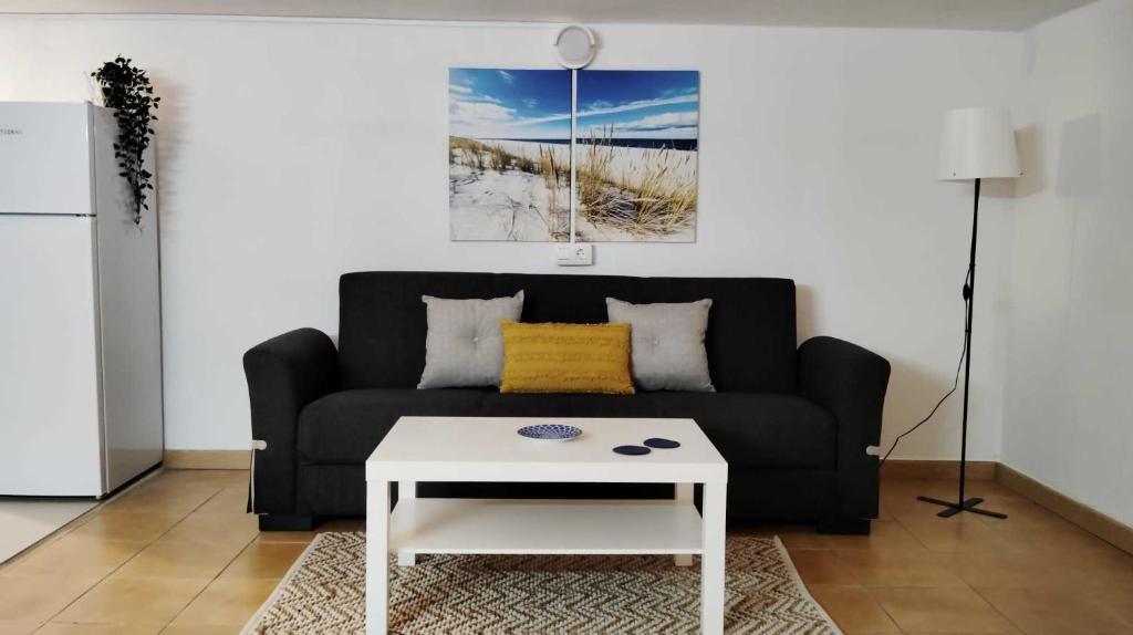 sala de estar con sofá negro y mesa de centro blanca en Amplio apartamento recién reformado en Tejina