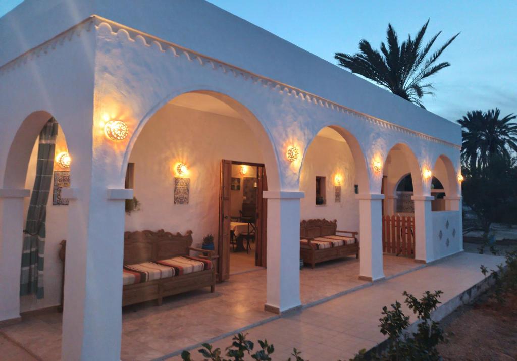 - un bâtiment blanc avec des canapés sur une terrasse dans l'établissement Djerba rêve vacances Noura, à Midoun