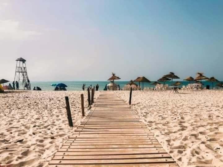 a wooden pathway on a beach with umbrellas at New appartement 2 chambres in Soliman