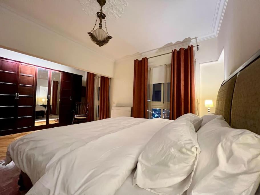 een groot wit bed in een slaapkamer met rode gordijnen bij Delightful 3BR home in Zamalek (no visits) in Caïro