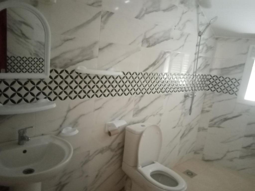 a white bathroom with a toilet and a sink at le ventoux in El Hajeb