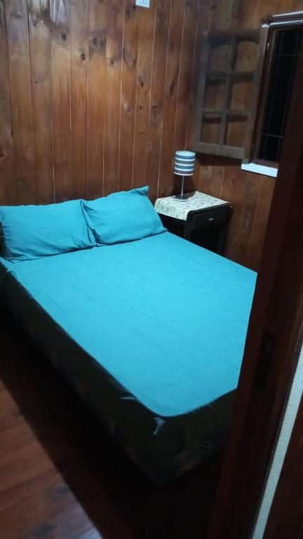 a bed with blue sheets in a wooden room at Cabañas Aliwen in Puerto Bossetti