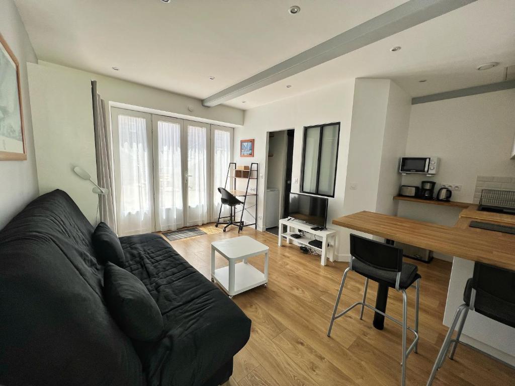 sala de estar con sofá negro y escritorio en Le Petit Malo - Sudio avec terrasse et parking privé, en La Rochelle