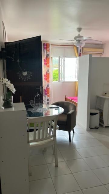 uma sala de estar com uma mesa e uma cadeira em Appartement F2 ROSALINDA em Les Abymes