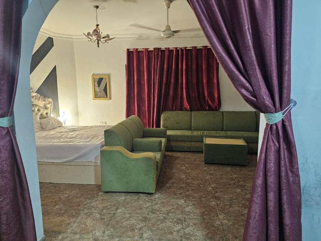 een slaapkamer met een bank en een bed met rode gordijnen bij apartment B1-9 in Muscat