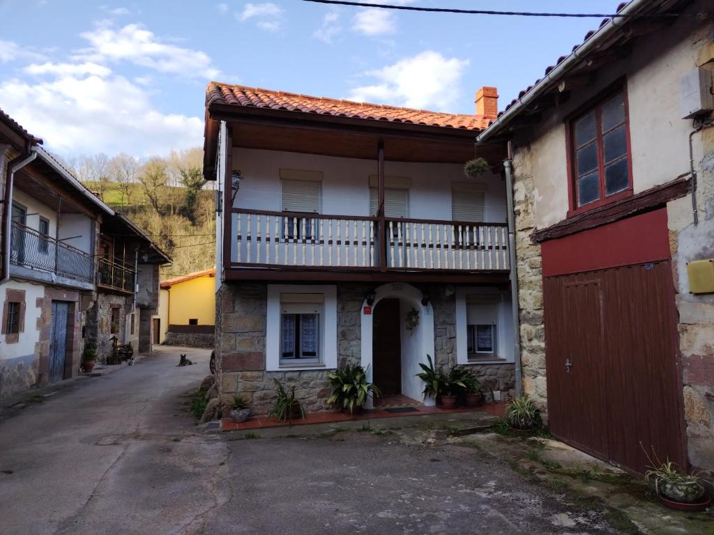 een oud huis met een balkon in een straat bij Casa Josefa in Villasuso de Cieza