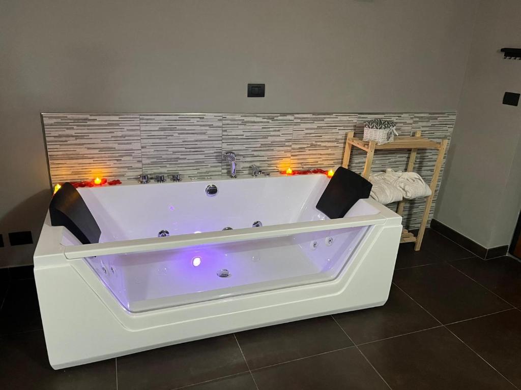 una gran bañera blanca en una habitación con luces en Fabianna suite, en Agliano Terme