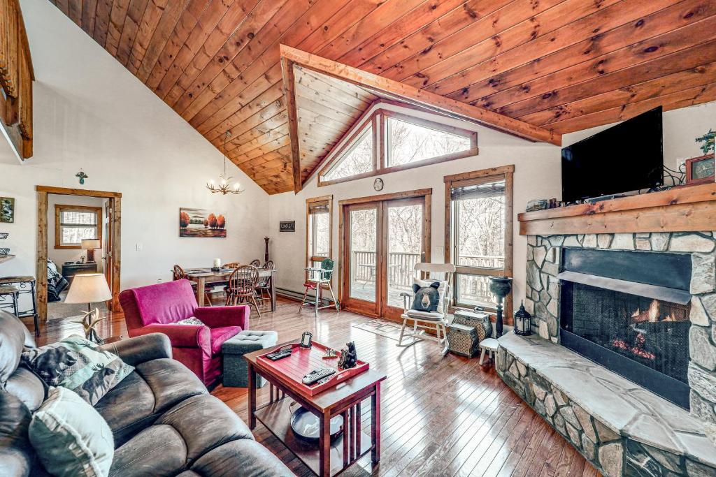 a living room with a stone fireplace and a tv at 1 Mi to Beech Mtn Skiing: Family Cabin w/ Fire Pit in Beech Mountain