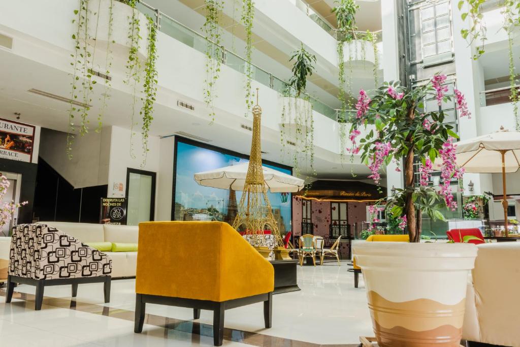 een lobby met gele stoelen, tafels en bloemen bij Paris FC Hotel in Poza Rica de Hidalgo