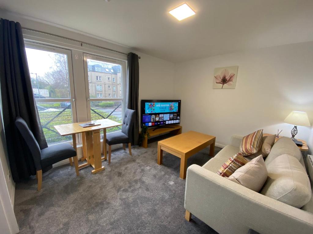 a living room with a couch and a table and a tv at East Coast City Centre Dunfermline Apartment in Fife