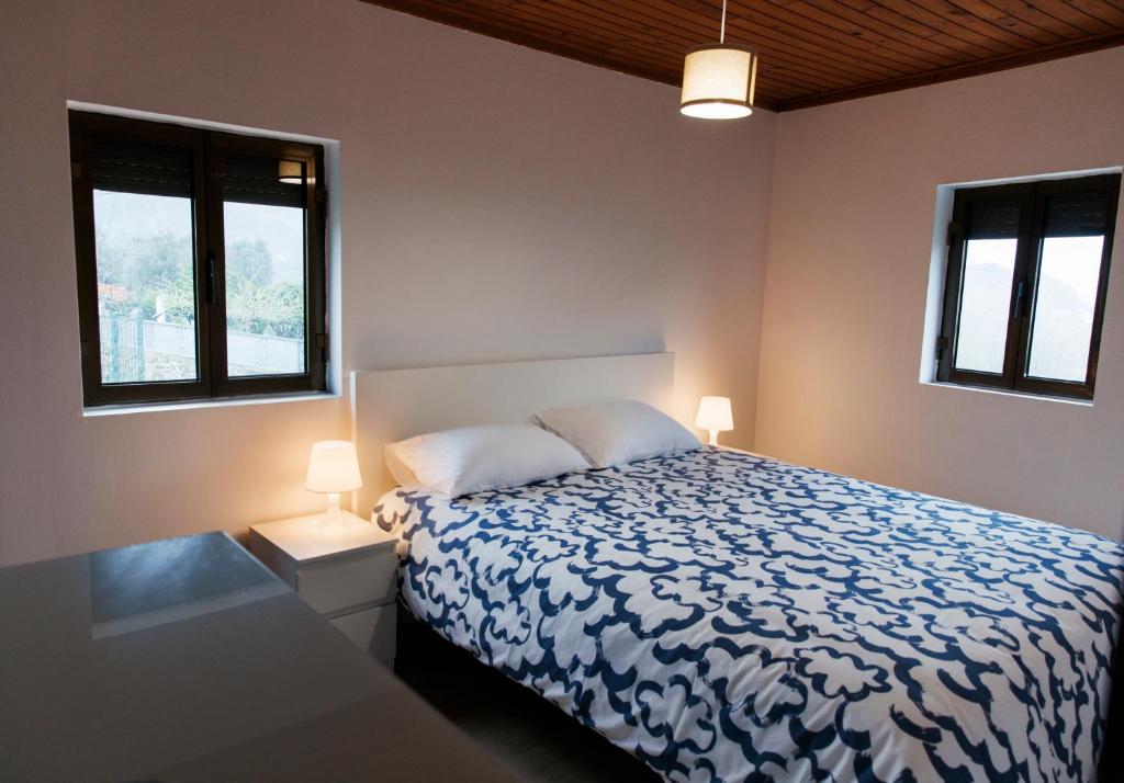 a bedroom with a bed and two windows at Casa da Laurinha in Arcos de Valdevez