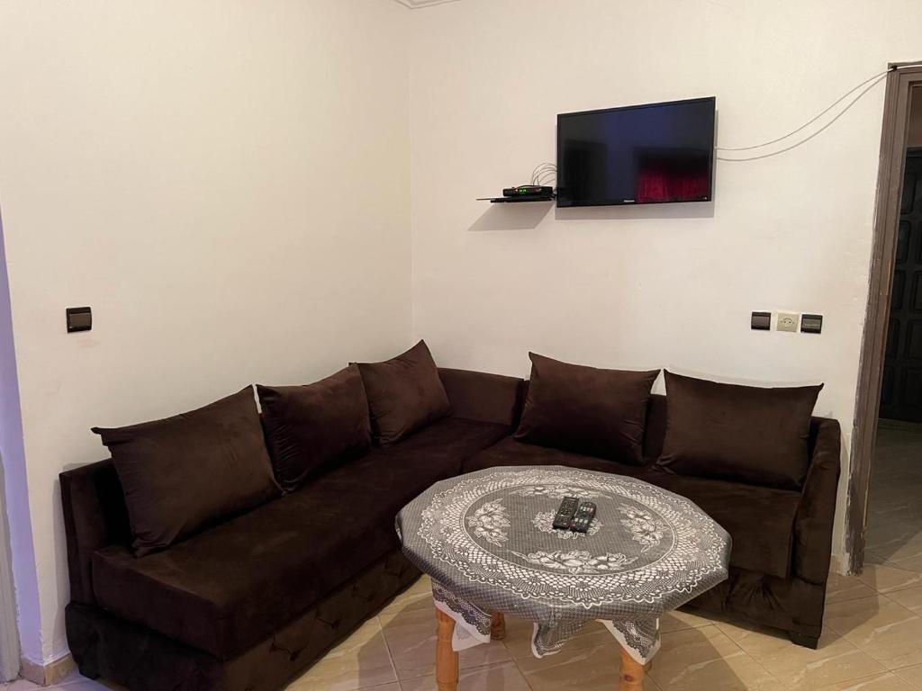 a living room with a brown couch and a table at appartements meublée nr 1 en rez-de-chaussée in Oujda