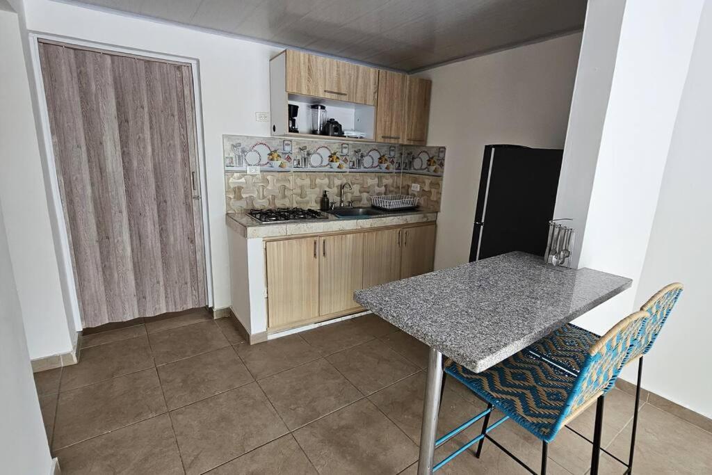 伊瓦格的住宿－Denier House Guabinal Apto 2，厨房配有桌子、炉灶和冰箱。