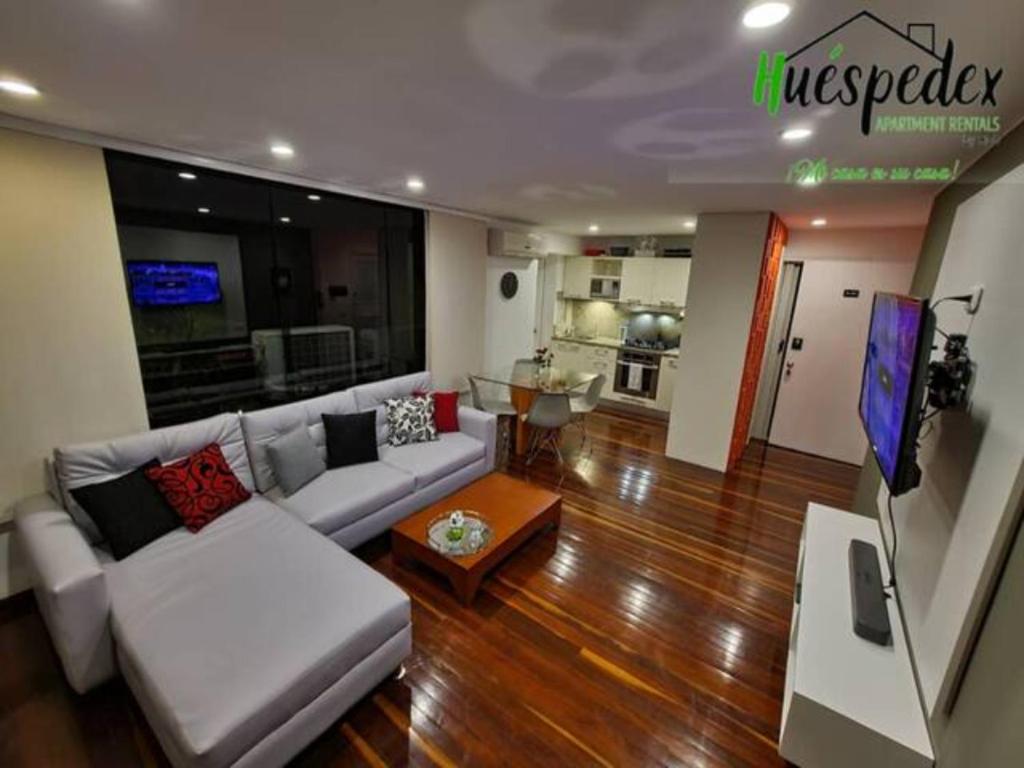 a living room with a white couch and a tv at Hermoso 1Hab+2baños apartamento en el Bosque,Ccs in Caracas