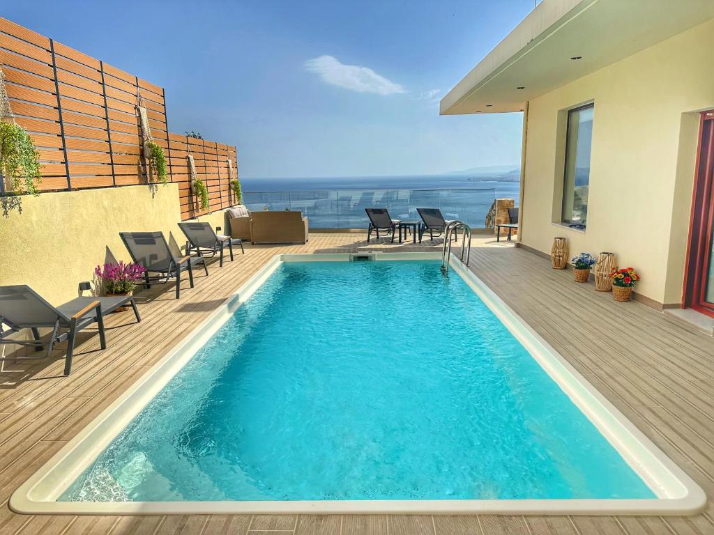 a swimming pool on a deck with chairs and a house at Villa Balcony, Cozy Villa with Amazing View in Rodia