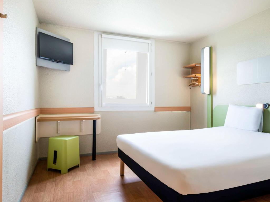 een slaapkamer met een wit bed en een raam bij ibis budget Paris Porte de Bercy in Charenton-le-Pont