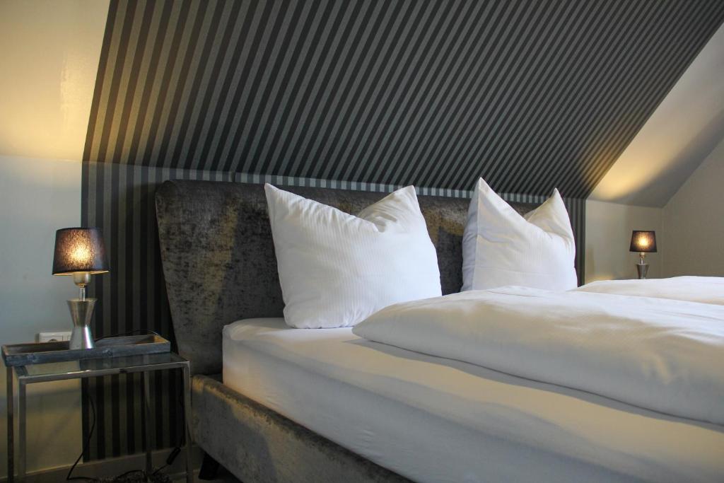 Habitación de hotel con cama con almohadas blancas en Huus am Meer en Norddeich