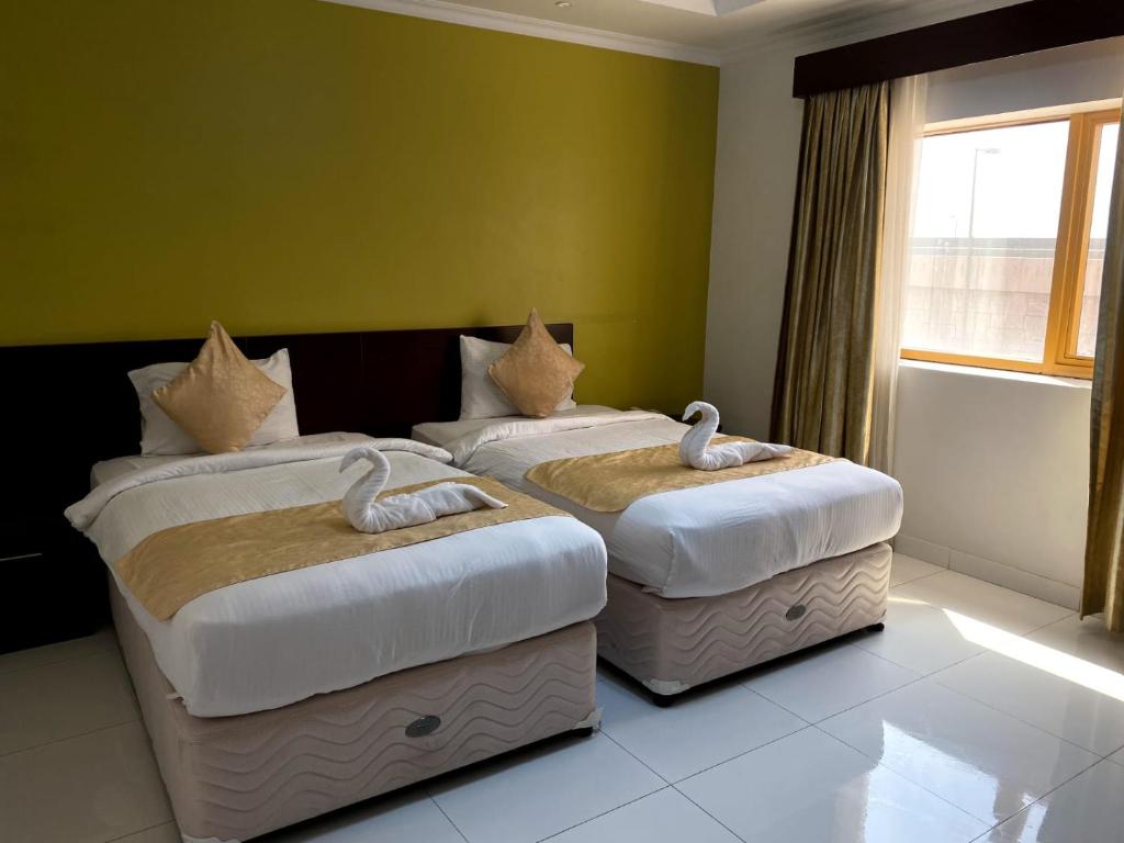 SADARA HOTELS APARTMENTS في صحار: سريرين في غرفة بجدران خضراء