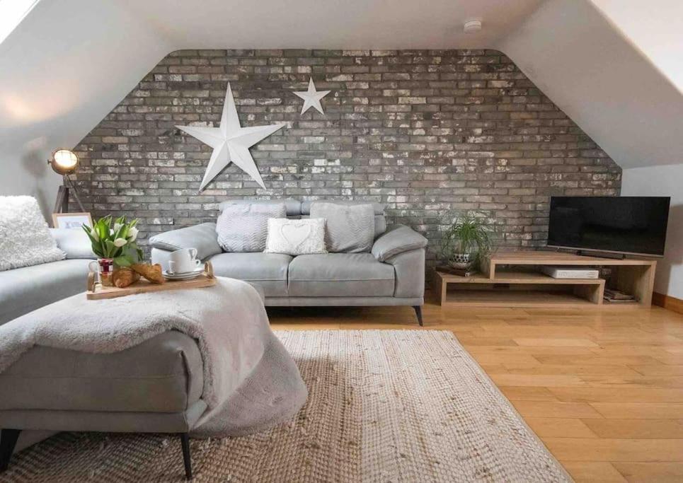 a living room with a couch and a brick wall at Creel Cottage (No. 4) in Arbroath