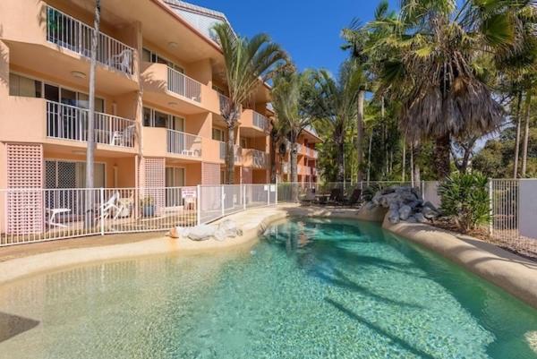 a swimming pool in front of a apartment building at Rainbow Sands Resort in Rainbow Beach